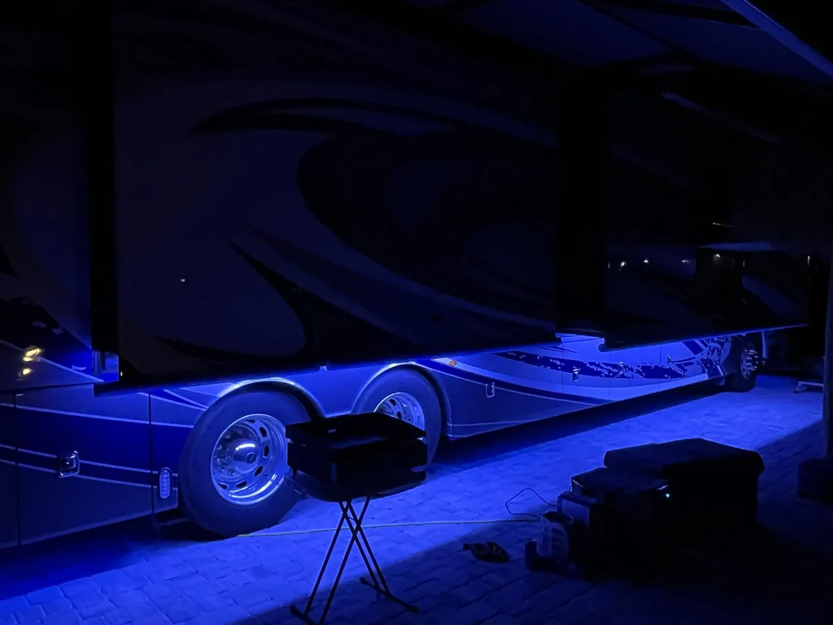 Class A motorhome with blue underglow at a campsite